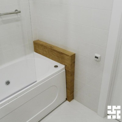 Длина ванны немного короче длины помещения. Полка из гипрока, отделанная плиткой с имитацией дерева, заполняет промежуток и украшает ванную
